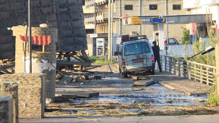 A man stands next to a vehicle near the last remaining bridge linking southern Lebanon to the rest of the country after it was struck on Wednesday by Israel, in Qasmiyeh, Lebanon, April 9, 2026. Picture taken with a mobile phone. REUTERS/Stringer