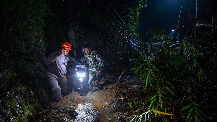 Petugas TNI dan Polri mengevakuasi pemotor yang terjebak longsoran di Cadas Pangeran, Kabupaten Sumedang, Jawa Barat, Rabu (8/4/2026). Longsor dari tebing setinggi 30 meter di Cadas Pangeran pada pukul 17.10 WIB akibat hujan lebat tersebut mengakibatkan akses jalan nasional yang menghubungkan Bandung-Cirebon ditutup total dan hingga pukul 20.30 WIB petugas gabungan masih menunggu alat berat untuk evakuasi material longsoran. ANTARA FOTO/Raisan Al Farisi/sgd