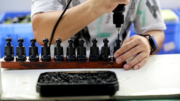 An employee works at an assembly line producing car smartphone holders at a plastic accessories factory, as rising oil prices drive up production costs for plastic manufacturers, in Dongguan, Guangdong province, China, April 2, 2026. REUTERS/Go Nakamura