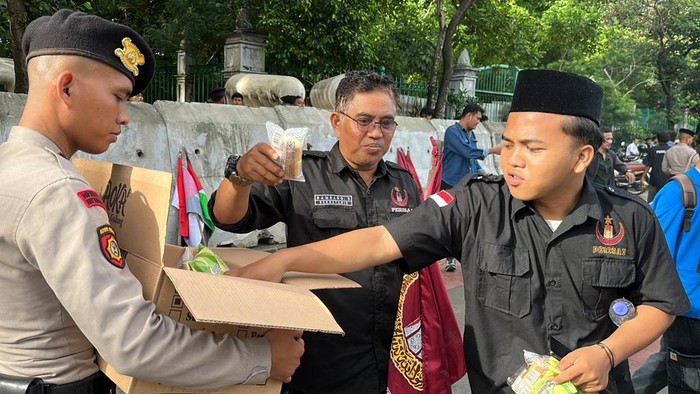 Polisi membagikan roti dan air mineral kepada massa demo di Monas, Jakpus, Kamis (9/4/2026).