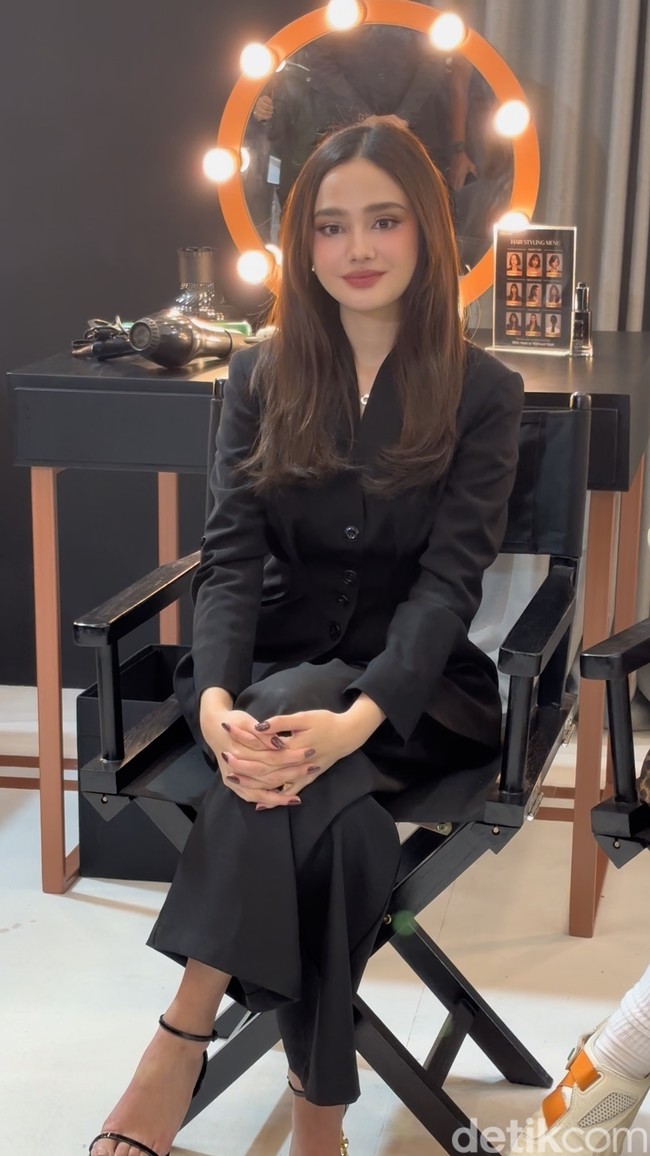 Syifa memilih busana rapi dan sopan dengan atasan lengan panjang dan celana panjang. Ia melengkapi penampilannya dengan strap heels senada. Foto: Wolipop/Vina Oktiani