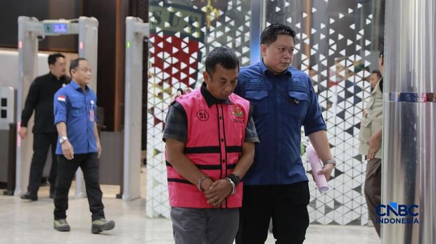 Tersangka kasus korupsi tata kelola minyak mentah berjalan menuju mobil tahanan di gedung Kejaksaan Agung, Jakarta, Kamis (9/4/2026) malam. (CNBC Indonesia/Muhammad Sabki)