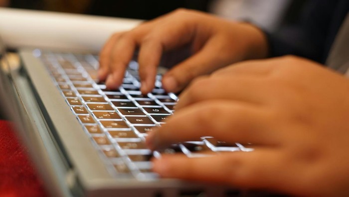 Tangan mengetik di laptop.