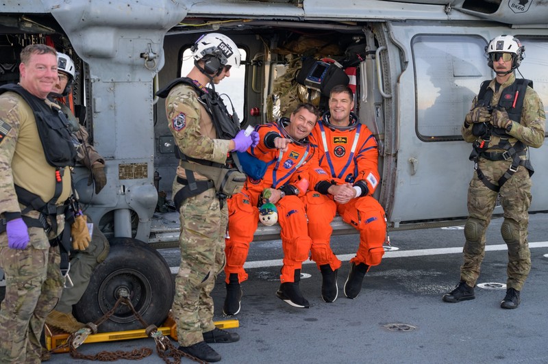 NASA astronaut Victor Glover, Artemis II pilot, left, and NASA astronaut Christina Koch, Artemis II mission specialist are seen sitting on a Navy MH-60 Seahawk from Helicopter Sea Combat Squadron (HSC) 23 on the flight deck of USS John P. Murtha after they and fellow crewmates CSA (Canadian Space Agency) astronaut Jeremy Hansen, Artemis II mission specialist, and NASA astronaut Reid Wiseman, Artemis II commander, were extracted from their Orion spacecraft after splashdown, Friday, April 10, 2026, in the Pacific Ocean off the coast of California. NASA’s Artemis II mission took the quartet on a nearly 10-day journey around the Moon and back to Earth. Following a splashdown at 5:07 p.m. PDT (8:07 p.m. EDT), NASA, U.S. Navy, and U.S. Air Force teams are working to bring the Orion spacecraft aboard the recovery ship.