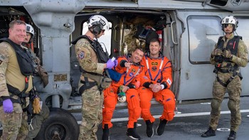Reid Wiseman dan Jeremy Hansen duduk di helikopter Seahawk di dek USS John P. Murtha usai dievakuasi dari kapsul Orion setelah splashdown di Samudra Pasifik, 10 April 2026, menutup misi Artemis II selama hampir 10 hari mengelilingi Bulan. Foto: NASA/Bill Ingalls