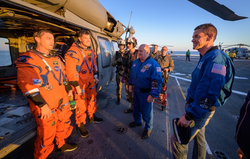 NASA astronaut Victor Glover, Artemis II pilot, left, and NASA astronaut Christina Koch, Artemis II mission specialist are seen sitting on a Navy MH-60 Seahawk from Helicopter Sea Combat Squadron (HSC) 23 on the flight deck of USS John P. Murtha after they and fellow crewmates CSA (Canadian Space Agency) astronaut Jeremy Hansen, Artemis II mission specialist, and NASA astronaut Reid Wiseman, Artemis II commander, were extracted from their Orion spacecraft after splashdown, Friday, April 10, 2026, in the Pacific Ocean off the coast of California. NASA’s Artemis II mission took the quartet on a nearly 10-day journey around the Moon and back to Earth. Following a splashdown at 5:07 p.m. PDT (8:07 p.m. EDT), NASA, U.S. Navy, and U.S. Air Force teams are working to bring the Orion spacecraft aboard the recovery ship.