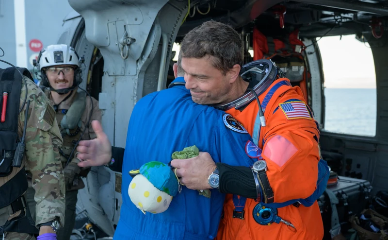 NASA astronaut Victor Glover, Artemis II pilot, left, and NASA astronaut Christina Koch, Artemis II mission specialist are seen sitting on a Navy MH-60 Seahawk from Helicopter Sea Combat Squadron (HSC) 23 on the flight deck of USS John P. Murtha after they and fellow crewmates CSA (Canadian Space Agency) astronaut Jeremy Hansen, Artemis II mission specialist, and NASA astronaut Reid Wiseman, Artemis II commander, were extracted from their Orion spacecraft after splashdown, Friday, April 10, 2026, in the Pacific Ocean off the coast of California. NASA’s Artemis II mission took the quartet on a nearly 10-day journey around the Moon and back to Earth. Following a splashdown at 5:07 p.m. PDT (8:07 p.m. EDT), NASA, U.S. Navy, and U.S. Air Force teams are working to bring the Orion spacecraft aboard the recovery ship.
