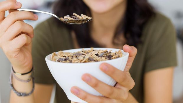 Portrait of beautiful young woman enjoying breakfast at home.