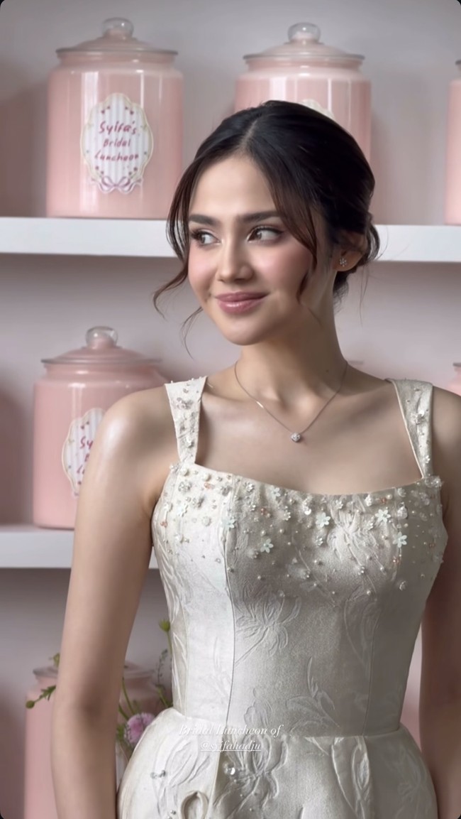 Di beberapa bagian gaun terdapat sentuhan payet kecil yang membuatnya tampak sedikit berkilau saat terkena cahaya. Ia mempermanis penampilannya dengan aksesori berupa anting dan kalung bermodel simpel yang elegan dan timeless. Foto: Instagram/@syifahadju