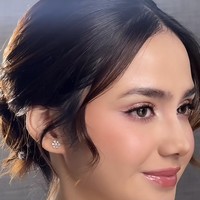 Riasan wajahnya terlihat flawless dengan soft glam look yang natural. Kulit tampak glowing dengan foundation ringan. Riasan mata tidak berlebihan, fokus pada bulu mata lentik dan eyeliner tipis. Blush on pink menambah efek segar, serta lipstik berwarna nude pink menambah kesan manis. Foto: Instagram/@syifahadju