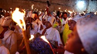 Mereka membawa lilin sebagai simbol harapan dan iman, yang nantinya akan dinyalakan dari Api Suci sebagai bagian dari ritual sakral. Para jemaah mengikuti setiap rangkaian dengan khusyuk, menegaskan kuatnya nilai spiritual yang dijunjung dalam tradisi ini. REUTERS/Florion Goga