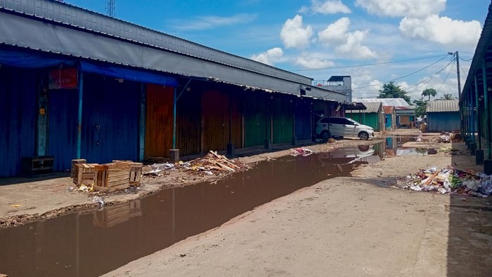 Kondisi jalanan rusak dan tergenang air serta sampah berserakan di Pasar Buah Induk Jakabaring, Palembang