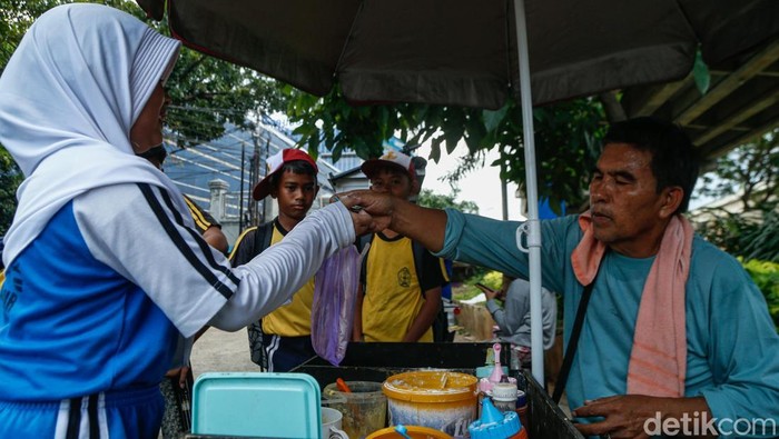 Penjual memberikan jajanan kepada pelanggan di Jakarta, Senin (13/4/2026).