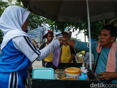 Penjual memberikan jajanan kepada pelanggan di Jakarta, Senin (13/4/2026).