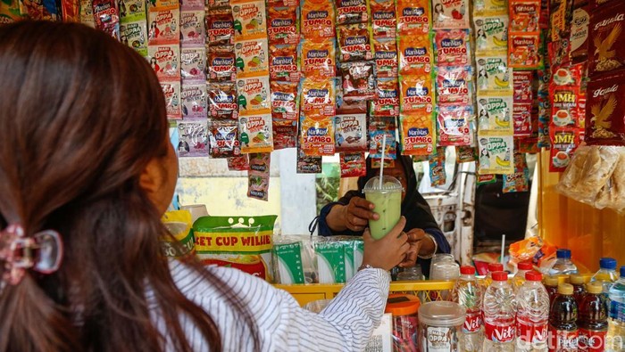 Penjual memberikan jajanan kepada pelanggan di Jakarta, Senin (13/4/2026).