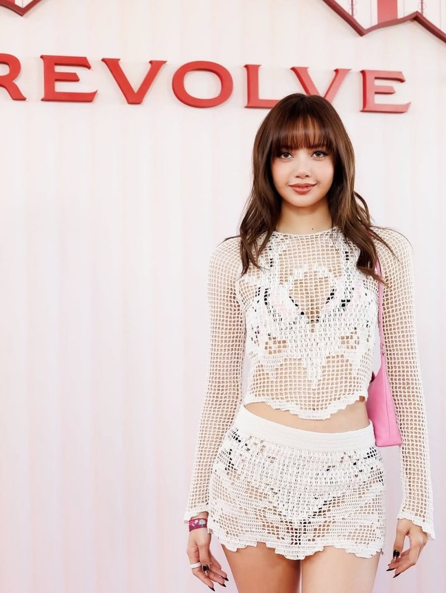 Menjadi tamu pesta ekslusif Revolve di Coachella 2026, Lisa mengandalkan tampilan white on white dengan material lace yang seduktif. Tas pink menjaga tampilannya jauh dari kesan monoton. (Foto: Instagram)