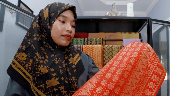 Ira Mutiara (33), pemilik rumah produksi Mutiara Songket, memperlihatkan kain songket khas Aceh di Aceh Besar, Aceh, Selasa (14/4/2026). Rumah produksi tersebut mampu memproduksi kain songket khas Aceh sebanyak 10 helai per bulan dengan beragam motif seperti Pintu Aceh, Bunga Lawang, dan Bunga Jeumpa yang dipasarkan ke berbagai daerah seperti Sumatera Utara, Sumatera Barat, Sulawesi, dan Jakarta dengan harga jual berkisar Rp800 ribu-Rp3 juta per helai serta turut dipamerkan pada ajang fesyen internasional di Prancis. ANTARA FOTO/Akramul Muslim