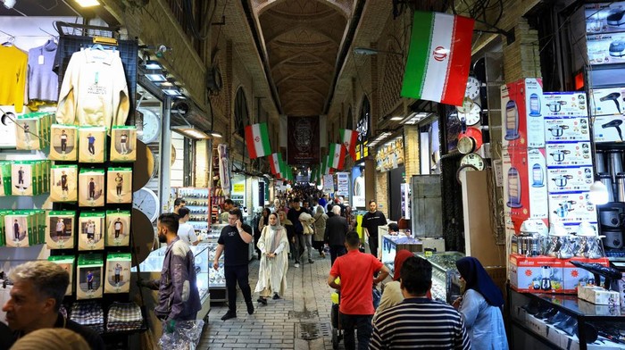 A craftsman repairs handwoven carpets inside a workshop at Tehrans Grand Bazaar in Iran, April 13, 2026. REUTERS/Thaier Al Sudani