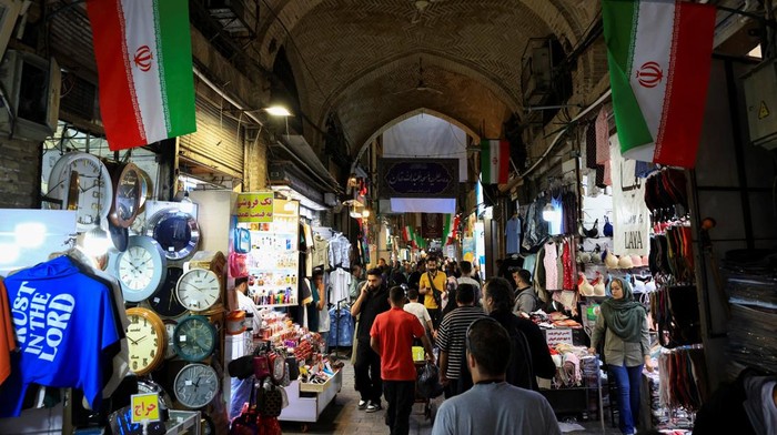 A craftsman repairs handwoven carpets inside a workshop at Tehran’s Grand Bazaar in Iran, April 13, 2026. REUTERS/Thaier Al Sudani