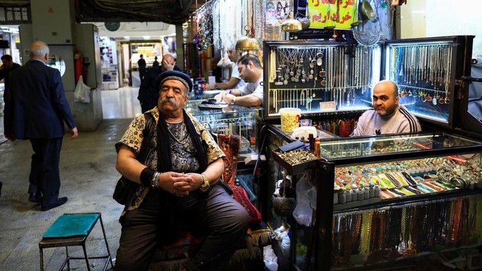 A craftsman repairs handwoven carpets inside a workshop at Tehran’s Grand Bazaar in Iran, April 13, 2026. REUTERS/Thaier Al Sudani
