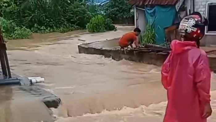 Sungai kecil di Muara Enim meluap hingga mengalir ke arah jalan.