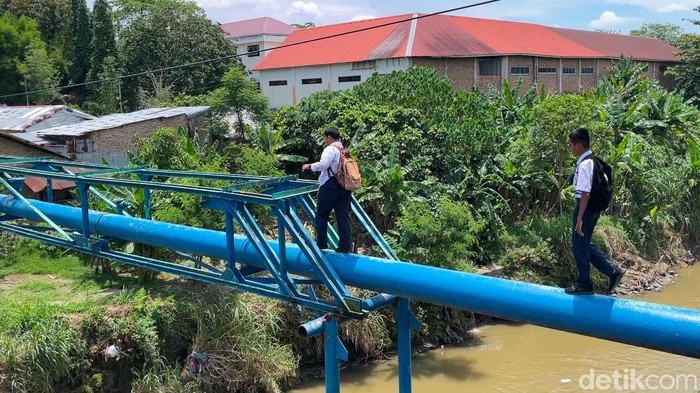 Anak SMP saat melewati pipa seusai pulang sekolah. (Foto: Finta Rahyuni/detikSumut)