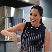 Lawatan kemudian berlanjut ke rumah penampungan tunawisma di mana Meghan menyiapkan makanan langsung di dapur. Busana yang sama masih dipakai, tapi kali ini dilapisi celemek. (Foto: Jonathan Brady/Pool via REUTERS)