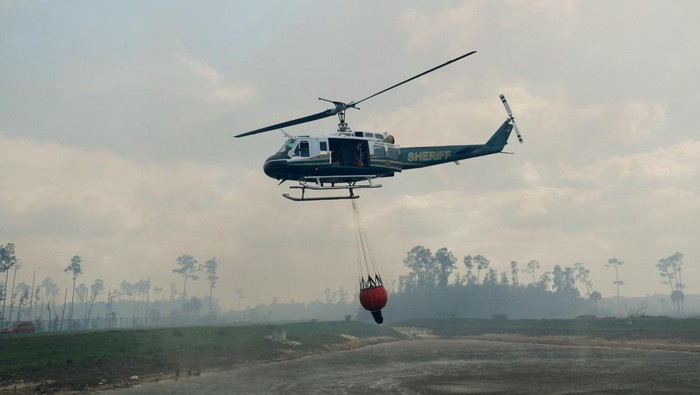 A helicopter flies as first responders with the Florida Fish and Wildlife Conservation Commission, Collier County Sheriff’s Office, and the U.S. Forest Service work to contain a brush fire at Picayune Strand State Forest in Naples, Florida, U.S., April 14, 2026. REUTERS/Octavio Jones
