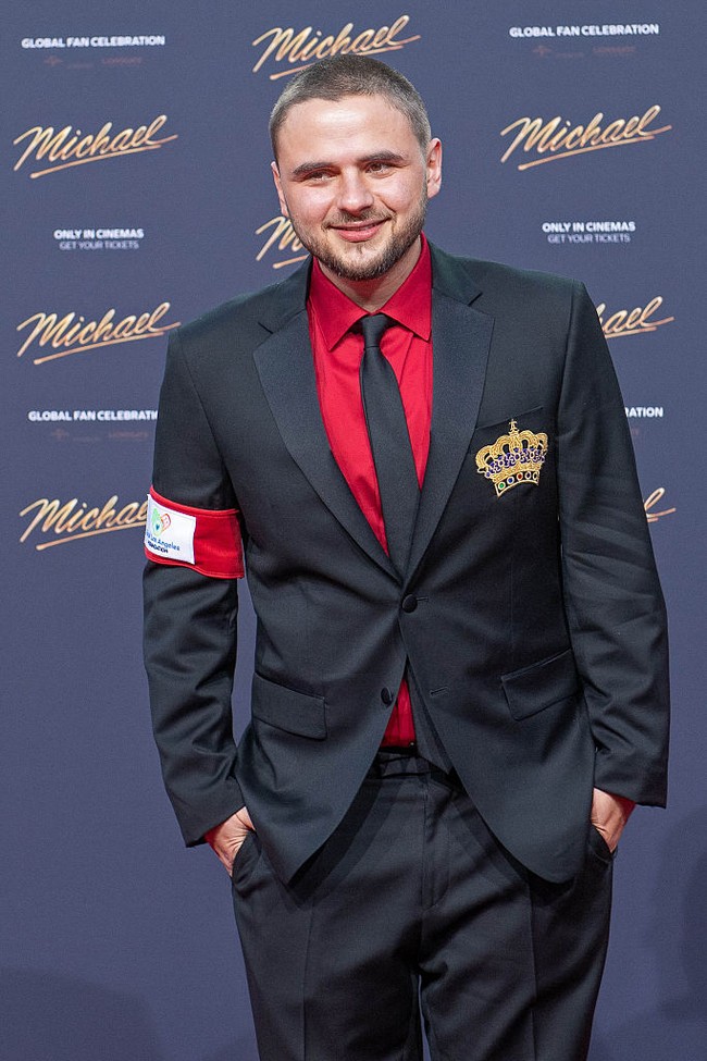 Kakak Bigi, Prince Jackson, memadukan jas hitam dengan kemeja merah. Pria 29 tahun ini terlihat selalu melempar senyum lebar ke awak media. Foto: WireImage/Tristar Media
