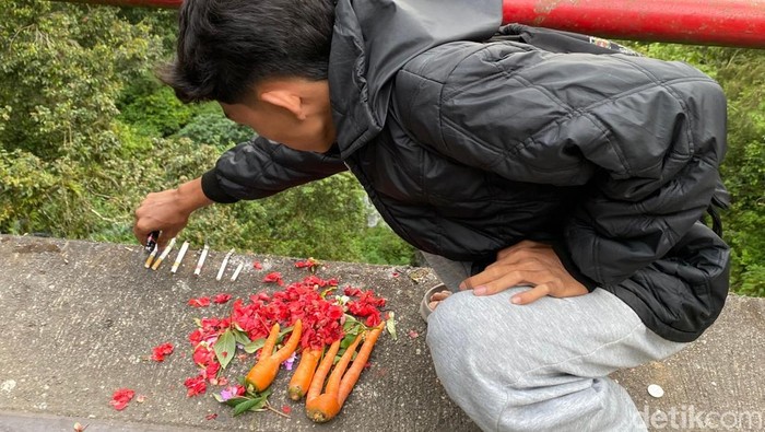 Salah satu pemuda meletakkan sebatang rokok yang baru dinyalakan di Jembatan Cangar