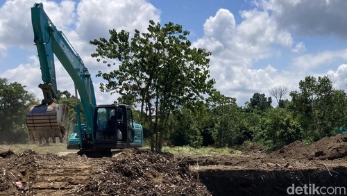 Sebuah alat berat dikerahkan untuk memasukkan tumpukan sampah organik yang sudah dicacah di area Embung Tukad Unda, Klungkung, Rabu (15/4/2026). (Foto: Fatih Kudus Jaelani/detikBali)