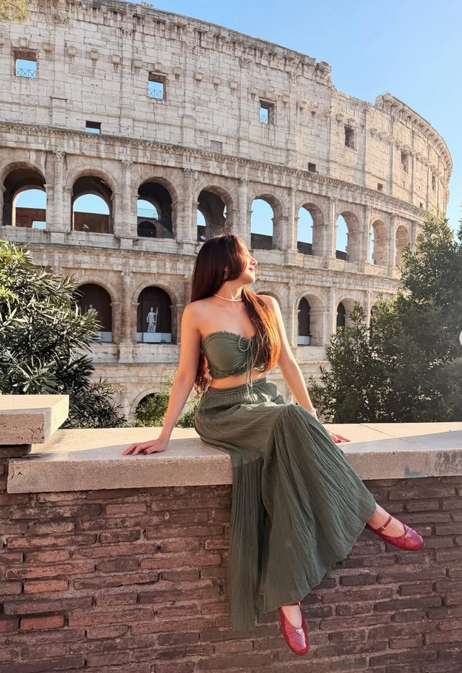 Di salah satu momen Angel tampak mengenakan setelan berwarna olive green. Strapless crop top berpadu rok panjang flowy membuat penampilan Angel terlihat feminin. Ia juga memadukannya dengan sepasang flat shoes merah dan kalung choker mutiara. Foto: Instagram/@realangelkaramoy