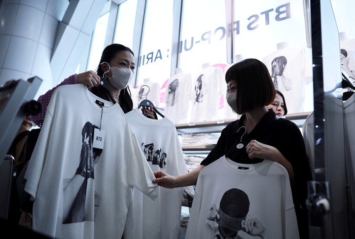 A fan of Kpop boy band BTS poses before the poster depicting the members at a pop-up store, ahead of the bands upcoming BTS World Tour Arirang concert, at Shibuya shopping and amusement district in Tokyo, Japan, April 16, 2026. REUTERS/Issei Kato