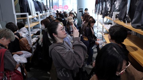 A fan of Kpop boy band BTS poses before the poster depicting the members at a pop-up store, ahead of the band's upcoming BTS World Tour 'Arirang' concert, at Shibuya shopping and amusement district in Tokyo, Japan, April 16, 2026. REUTERS/Issei Kato