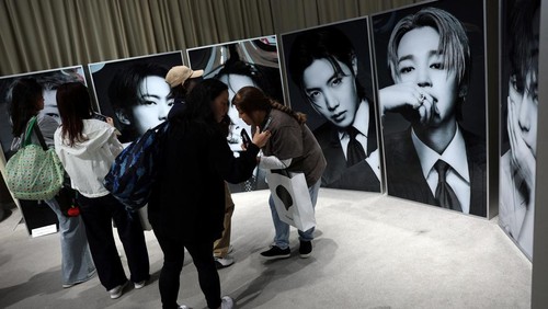 A fan of Kpop boy band BTS poses before the poster depicting the members at a pop-up store, ahead of the band's upcoming BTS World Tour 'Arirang' concert, at Shibuya shopping and amusement district in Tokyo, Japan, April 16, 2026. REUTERS/Issei Kato