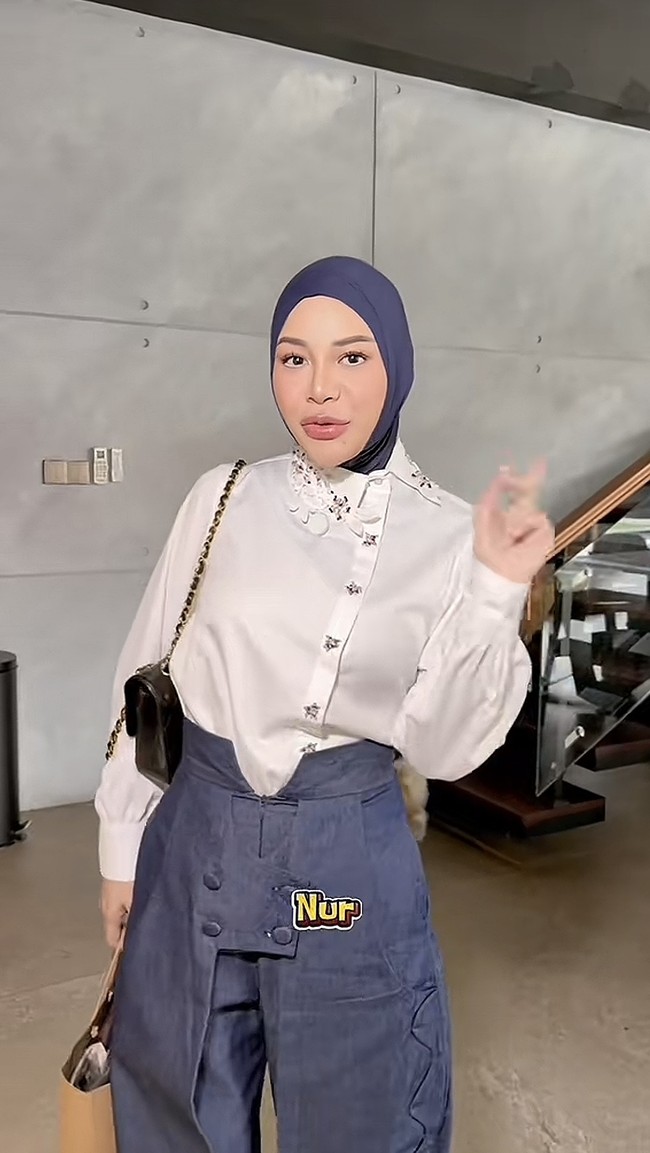 Aurel tampil kenakan kemeja putih dan celana panjang warna biru. Ia memilih gaya hijab dengan bagian bawah dimasukkan ke dalam kemeja yang dikenakan. Foto: TikTok/@aureliehermansyahatta