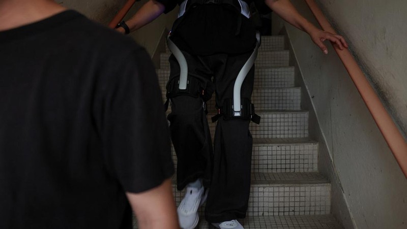 Betty Ho, a resident of Wang Fuk Court, tries on a robotic exoskeleton ahead of her first visit home to retrieve belongings after a deadly fire last year, in Hong Kong, China, April 14, 2026. REUTERS/Tyrone Siu     TPX IMAGES OF THE DAY