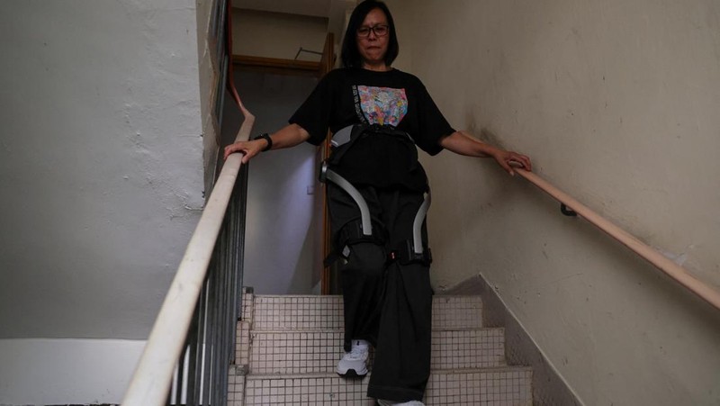 Betty Ho, a resident of Wang Fuk Court, tries on a robotic exoskeleton ahead of her first visit home to retrieve belongings after a deadly fire last year, in Hong Kong, China, April 14, 2026. REUTERS/Tyrone Siu     TPX IMAGES OF THE DAY