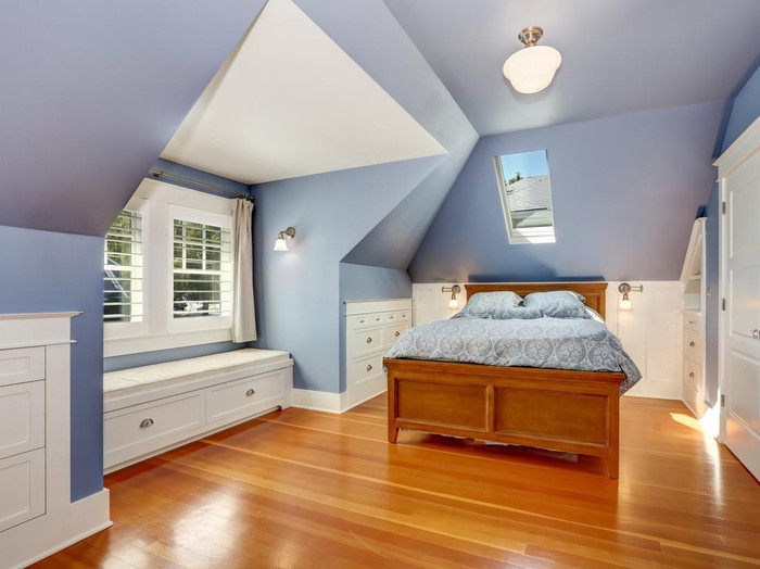 Lavender interior of attic bedroom with queen size bed and hardwood floor. Also window seat and built-in cabinets. Northwest, USA