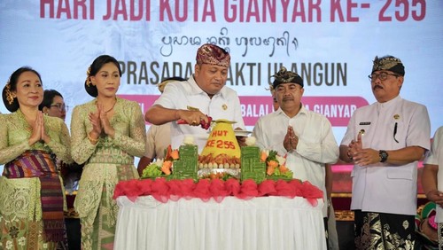 Bupati Gianyar, I Made Mahayastra, memotong nasi tumpeng saat apel peringatan HUT ke-255 Kota Gianyar di Alun-alun Gianyar, Minggu (19/4/2026). (Dok. Pemkab Gianyar)