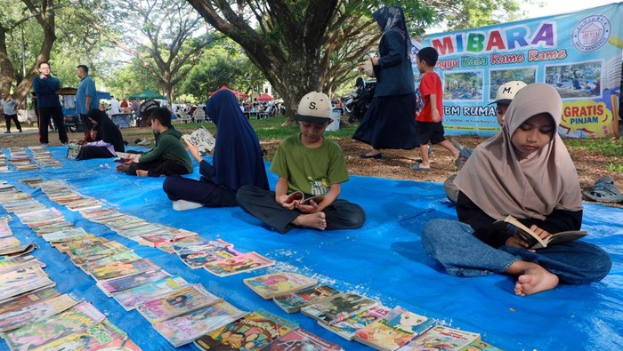Pengunjung bersama anaknya memilih buku pada kegiatan Minggu Baca Ramai Ramai (MIBARA) yang digelar Pustaka Ruman Aceh di ruang terbuka hijau Blang Padang, Banda Aceh, Aceh, Minggu (19/4/2026). Kegiatan literasi gratis yang rutin digelar setiap hari Minggu tersebut bertujuan memudahkan anak mengakses beragam bahan bacaan secara inklusif dan menumbuhkan minat baca sejak dini, serta mendukung implementasi Peraturan Pemerintah (PP) Tunas dalam melindungi anak dari dampak negatif paparan dunia digital. ANATARA FOTO/Akramul Muslim/hma