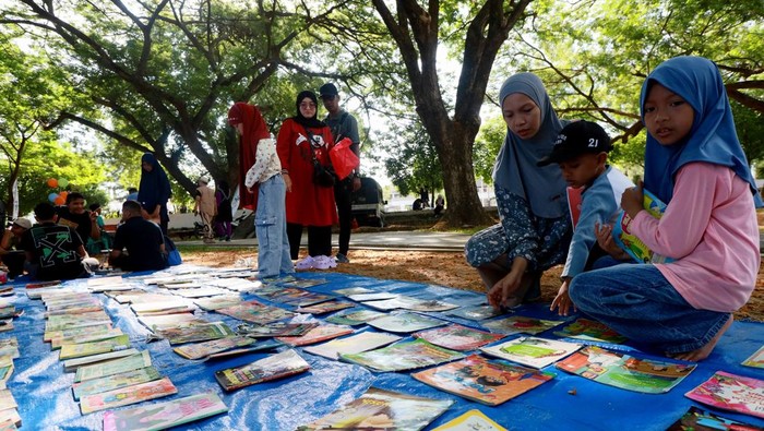 Pengunjung bersama anaknya memilih buku pada kegiatan Minggu Baca Ramai Ramai (MIBARA) yang digelar Pustaka Ruman Aceh di ruang terbuka hijau Blang Padang, Banda Aceh, Aceh, Minggu (19/4/2026). Kegiatan literasi gratis yang rutin digelar setiap hari Minggu tersebut bertujuan memudahkan anak mengakses beragam bahan bacaan secara inklusif dan menumbuhkan minat baca sejak dini, serta mendukung implementasi Peraturan Pemerintah (PP) Tunas dalam melindungi anak dari dampak negatif paparan dunia digital. ANATARA FOTO/Akramul Muslim/hma