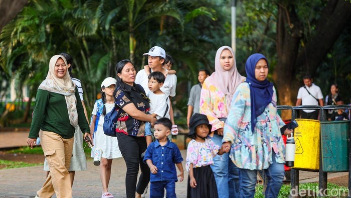 Keluarga berjalan santai di kawasan Monumen Nasional menikmati suasana sore Jakarta, Minggu (19/4/2026).