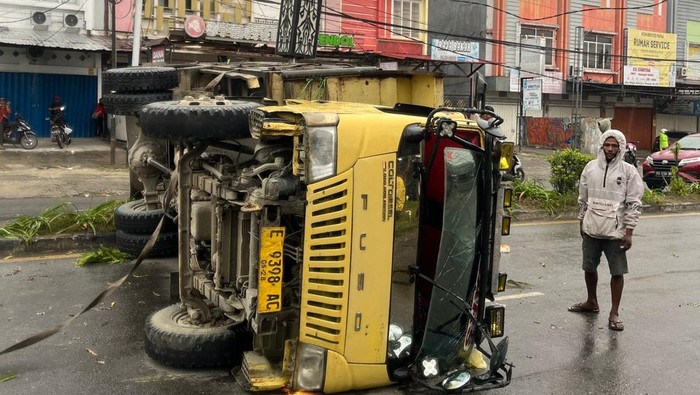 Sebuah truk terguling di Jayapura saat sopir menghindari pemotor, mengakibatkan 19 penumpang terluka.