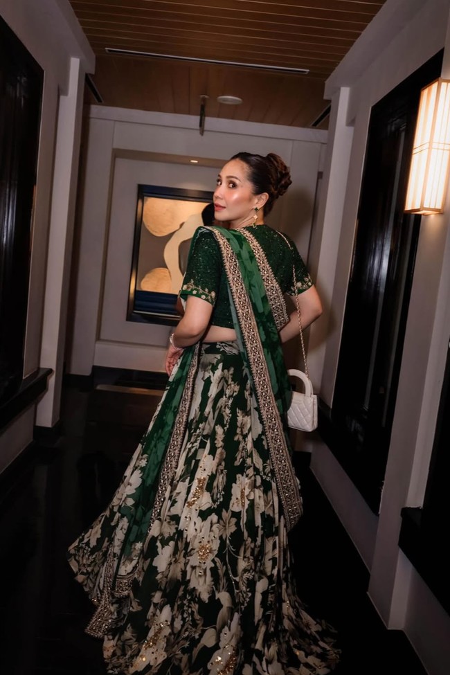 Nagita tampil lebih glam dengan lehenga hijau emerald yang dipenuhi bordir emas dan silver. Lehenga tersebut juga dipenuhi dengan motif floral yang cantik. Ia melengkapi penampilannya dengan selendang panjang dupatta yang disampirkan di bahu. Foto: Instagram/@raffinagita1717