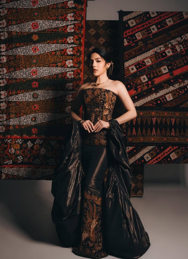 Davina Karamoy cantik dan glamor berbalut gaun Batik dan outer satin hitam. Busana dari koleksi An’Soe. “Honoring the legacy of Kartini: where elegance meets empowerment,” tulis Davina. Foto: Instagram