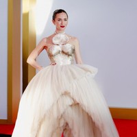 Emily Blunt menghadirkan kontras terhadap nuansa merah lembut rekan-rekannya dengan gaun bertekstur dari koleksi Schiaparelli haute couture Spring 2026 karya Daniel Roseberry. Desain tersebut menampilkan rok tulle asimetris berlapis yang terbelah di bagian tengah dan belakang menyerupai air mancur. (Foto: REUTERS/Jeenah Moon)