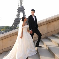 Rok gaun dibuat mengembang dengan ekor panjang yang menjuntai, menciptakan efek megah saat difoto di tangga dengan latar belakang Menara Eiffel. Ia melengkapi tampilannya dengan veil transparan panjang yang jatuh halus dari kepala, memberikan sentuhan klasik. Foto: Instagram/@jennifercoppenreal