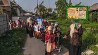 Dengan langkah riang, anak-anak berjalan beriringan dalam pawai kecil sambil memperagakan pakaian yang mereka kenakan, menciptakan suasana meriah sekaligus edukatif.