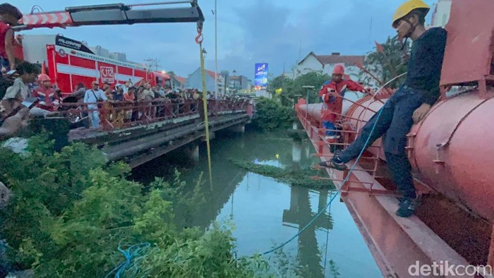Petugas Rescue Damkar Surabaya mengevakuasi motor 2 pejambret di Jembatan Merah Surabaya disaksikan warga sekitar.